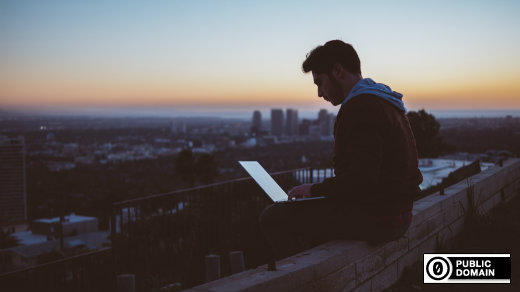 Person programming on a laptop on a building