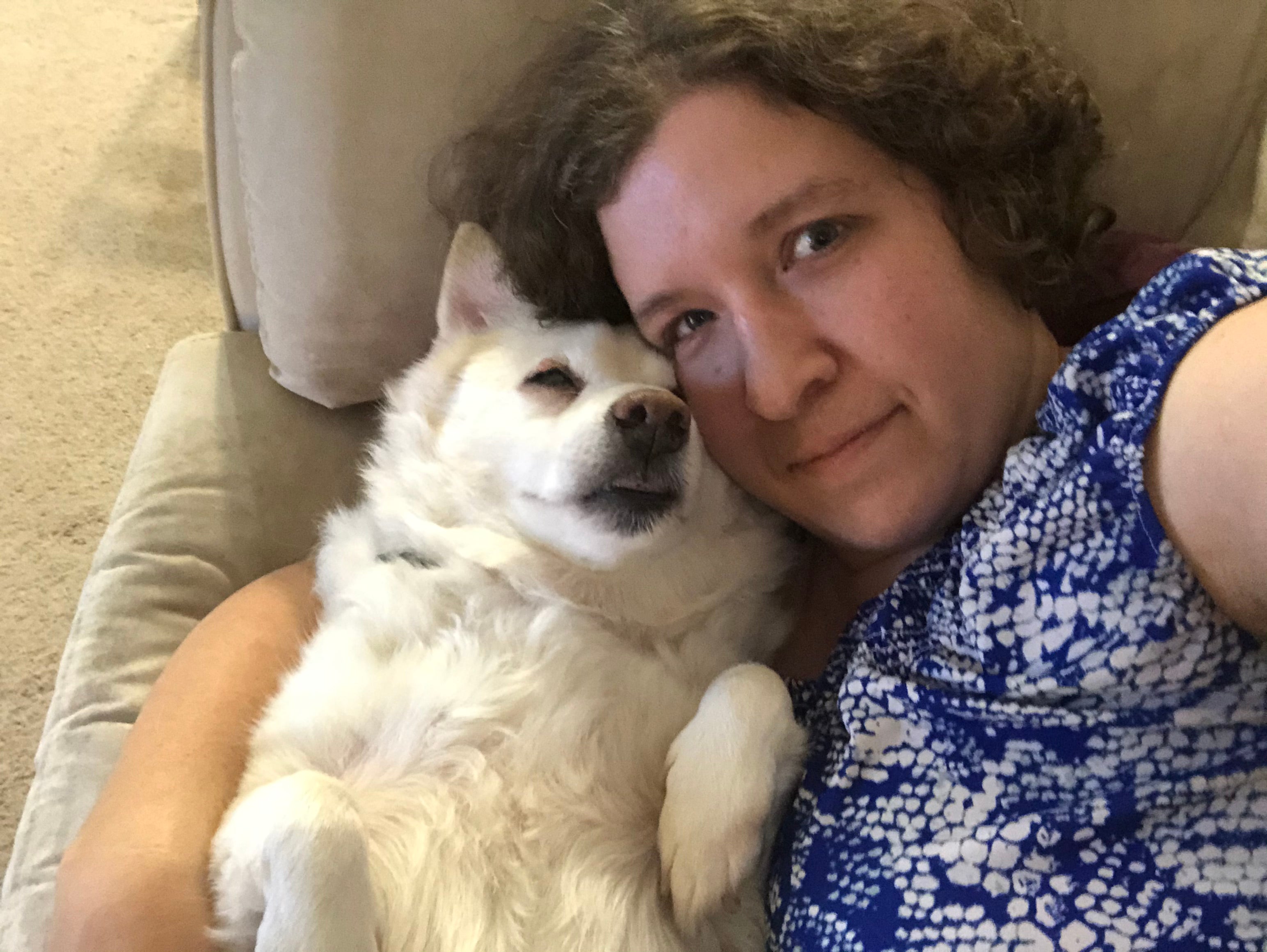 Miriam and her dog, Sasha, lying on the couch together.