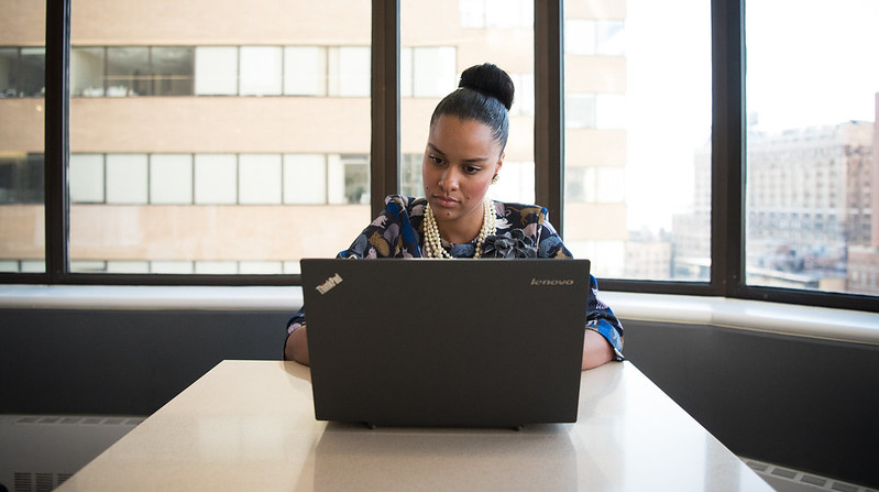 Woman using laptop concentrating Business woman on laptop sitting in front of window